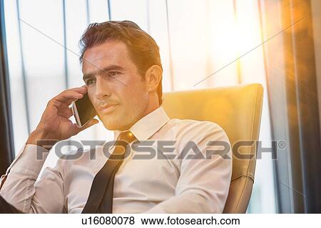 Mature businessman talking on smartphone with yellow lens flare View Large Photo Image Stock Photo - Mature businessman talking on smartphone with yellow lens flare. Fotosearch