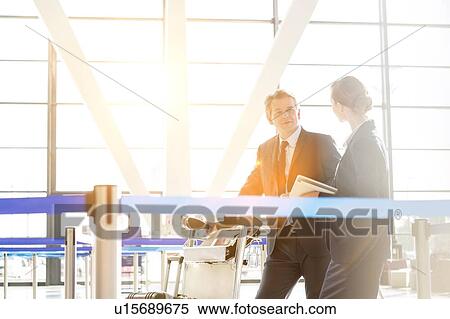 Stock Photography - Mature businessman talking with his business partner in check in are at airport. Fotosearch