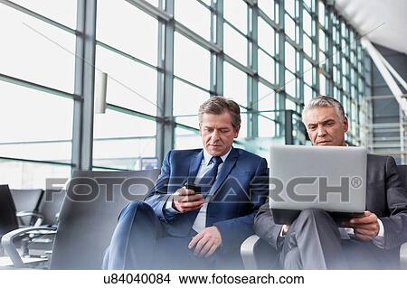 Picture - Mature businessman waiting for boarding in airport. Fotosearch