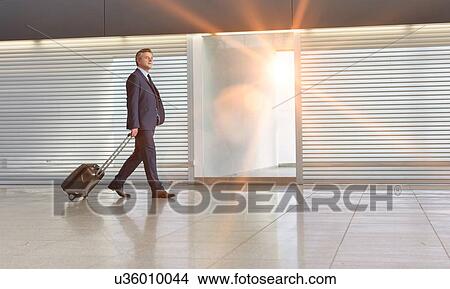 Picture - Mature businessman walking with his suitcase in the airport. Fotosearch