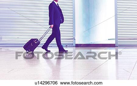 Stock Photograph - Mature businessman walking with his suitcase in the airport. Fotosearch
