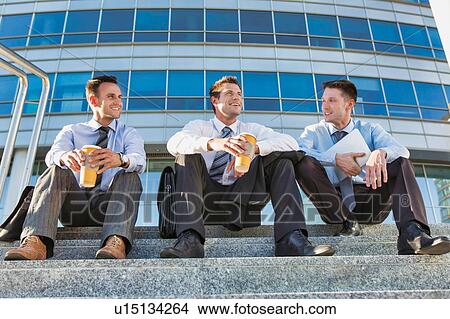 Picture - Mature businessmen sitting on stairs against office building after work. Fotosearch