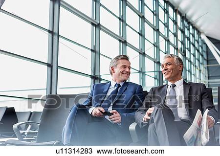Mature businessmen talking while sitting and waiting for boarding in airport View Large Photo Image Stock Image - Mature businessmen talking while sitting and waiting for boarding in airport . Fotosearch