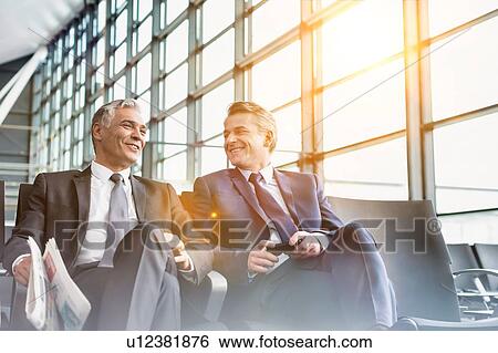 Mature businessmen talking while sitting and waiting for boarding in airport View Large Photo Image Stock Photograph - Mature businessmen talking while sitting and waiting for boarding in airport . Fotosearch