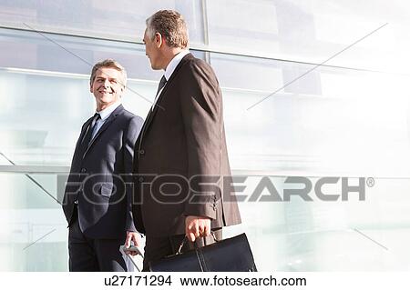 Mature businessmen walking while talking in the airport View Large Photo Image Picture - Mature businessmen walking while talking in the airport. Fotosearch