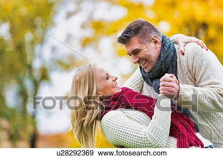 Stock Photo - Mature couple enjoying autumn and showing affection in park. Fotosearch