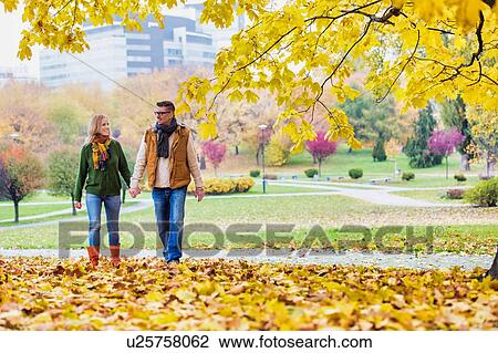 Mature couple enjoying autumn while walking in park in park View Large Photo Image Stock Image - Mature couple enjoying autumn while walking in park in park. Fotosearch