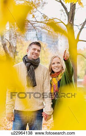 Mature couple enjoying autumn while walking in park in park View Large Photo Image Stock Photo - Mature couple enjoying autumn while walking in park in park. Fotosearch