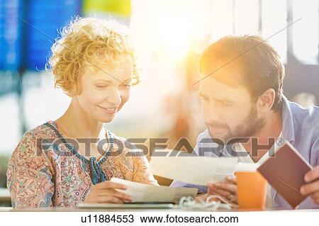 Stock Image - Mature couple looking at their boarding pass in airport. Fotosearch