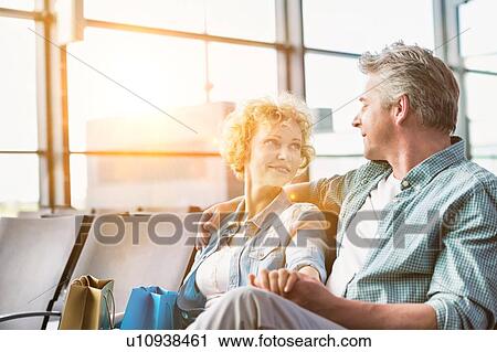 Stock Image - Mature couple sitting while waiting for their flight in airport. Fotosearch