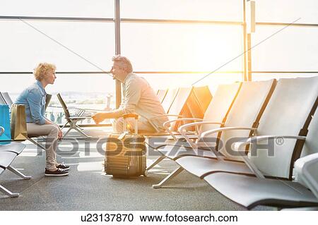 Mature couple sitting while waiting for their flight in airport View Large Photo Image Stock Image - Mature couple sitting while waiting for their flight in airport. Fotosearch
