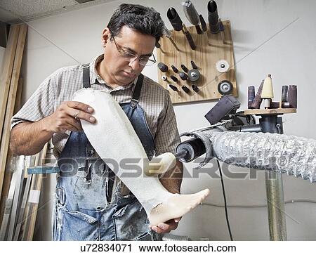 Stock Image - Mature male worker buffing prosthetic limb. Fotosearch