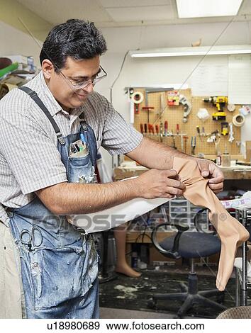 Stock Photo - Mature male worker working on prosthetic limb. Fotosearch