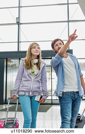 Stock Image - Mature man arriving with his daughter in airport looking for their pick up . Fotosearch