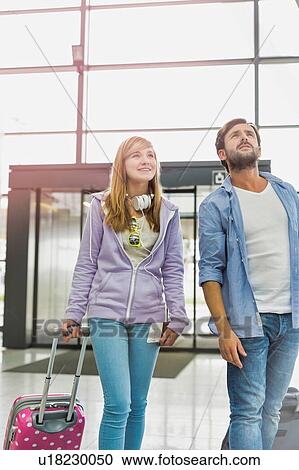 Stock Image - Mature man arriving with his daughter in airport looking for their pick up . Fotosearch