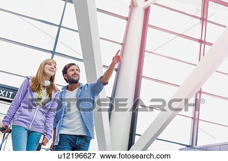 Stock Photo - Mature man arriving with his daughter in airport looking for their pick up . Fotosearch
