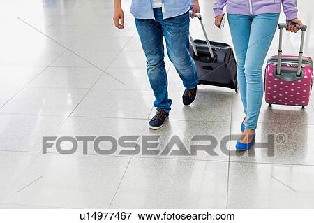 Stock Photo - Mature man arriving with his daughter in airport looking for their pick up . Fotosearch