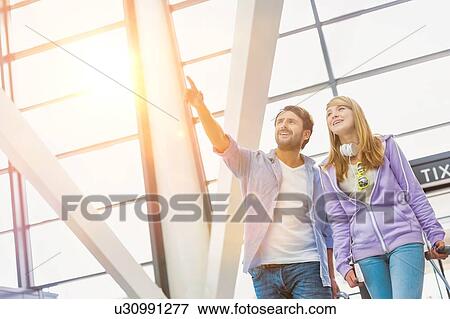 Stock Photo - Mature man arriving with his daughter in airport looking for their pick up . Fotosearch