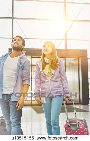 Stock Photography - Mature man arriving with his daughter in airport looking for their pick up . Fotosearch