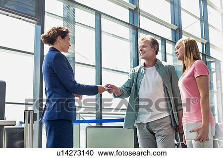 Mature man giving his passport and boarding pass with his daughter to airport staff in airport View Large Photo Image Stock Image - Mature man giving his passport and boarding pass with his daughter to airport staff in airport. Fotosearch