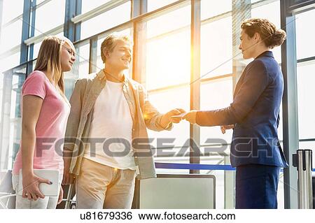 Mature man giving his passport and boarding pass with his daughter to airport staff in airport View Large Photo Image Stock Photograph - Mature man giving his passport and boarding pass with his daughter to airport staff in airport. Fotosearch