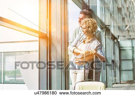 Mature man hugging his wife from behind while looking through the window in airport View Large Photo Image Stock Image - Mature man hugging his wife from behind while looking through the window in airport. Fotosearch