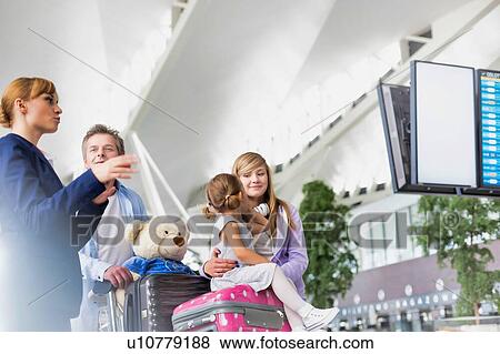 Stock Photo - Mature man traveling with two daughters asking for assistance with the airport staff . Fotosearch