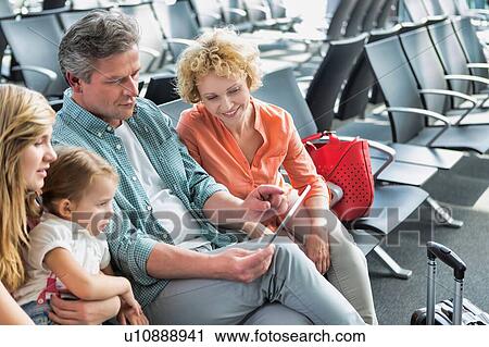 Mature man using digital tablet while his wife and daughter looking in airport View Large Photo Image Stock Image - Mature man using digital tablet while his wife and daughter looking in airport. Fotosearch