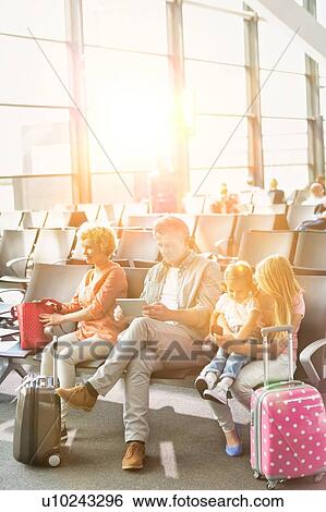 Stock Photograph - Mature man using digital tablet while sitting and waiting for boarding in airport. Fotosearch