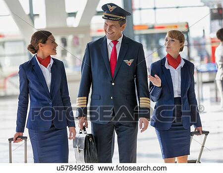 Stock Photograph - Mature pilot walking with two attractive flight attendants in airport. Fotosearch