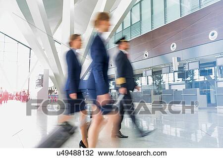 Mature pilot with young beautiful flight attendants walking in airport View Large Photo Image Stock Image - Mature pilot with young beautiful flight attendants walking in airport. Fotosearch