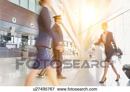 Mature pilot with young beautiful flight attendants walking in airport View Large Photo Image Stock Photo - Mature pilot with young beautiful flight attendants walking in airport. Fotosearch