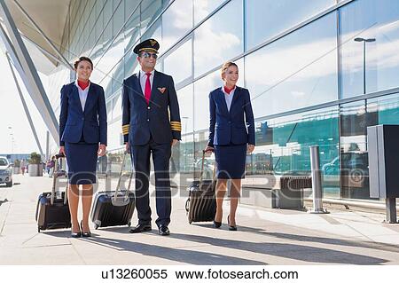 Mature pilot with young beautiful flight attendants walking in airport View Large Photo Image Stock Photography - Mature pilot with young beautiful flight attendants walking in airport. Fotosearch