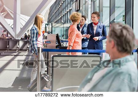 Stock Image - Mature woman on board giving her passport and boarding pass in airport. Fotosearch