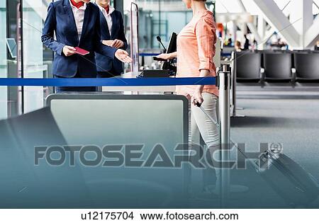 Picture - Mature woman on board scanning her ticket on smartphone in airport. Fotosearch
