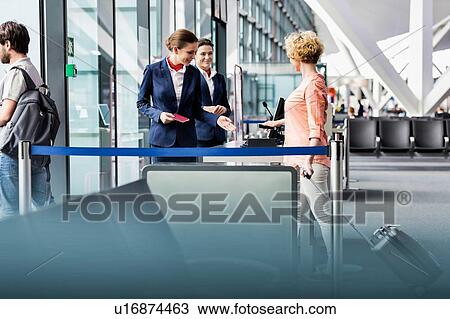 Stock Image - Mature woman on board scanning her ticket on smartphone in airport. Fotosearch