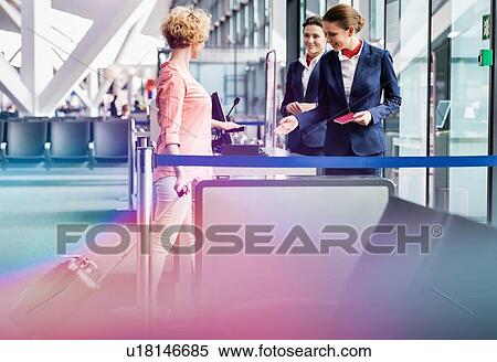 Stock Photography - Mature woman on board scanning her ticket on smartphone in airport. Fotosearch