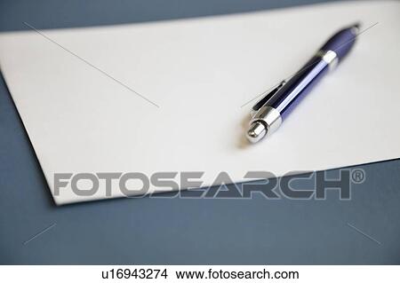 Picture - Metallic pen on a blank white paper over dark blue background. Fotosearch