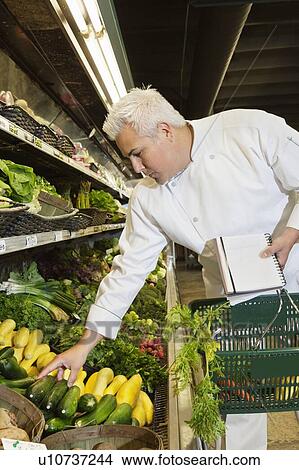 Mid adult chef looking at vegetables in market View Large Photo Image Picture - Mid adult chef looking at vegetables in market. Fotosearch