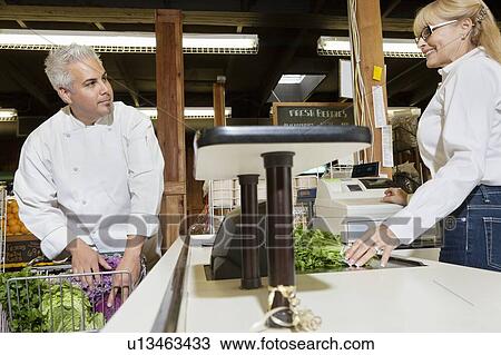 Mid adult chef with shopping cart standing at checkout counter with senior female employee in market View Large Photo Image Stock Image - Mid adult chef with shopping cart standing at checkout counter with senior female employee in market. Fotosearch