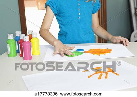 Mid section of a young girl finger painting on paper at table View Large Photo Image Stock Photograph - Mid section of a young girl finger painting on paper at table. Fotosearch