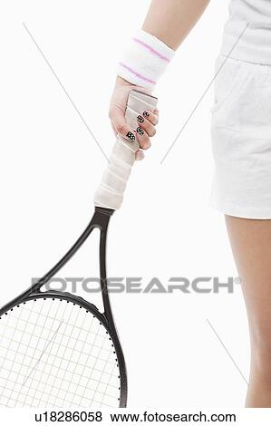 Stock Photo - Midsection of a young Asian woman holding tennis racket over white background. Fotosearch