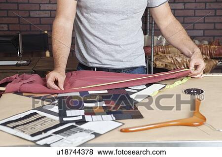 Midsection of male fashion designer taking measurement of shirt View Large Photo Image Stock Photo - Midsection of male fashion designer taking measurement of shirt. Fotosearch