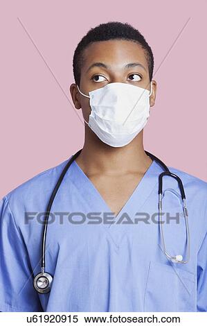 Mixed race male surgeon wearing surgical mask over pink background View Large Photo Image Stock Photography - Mixed race male surgeon wearing surgical mask over pink background. Fotosearch