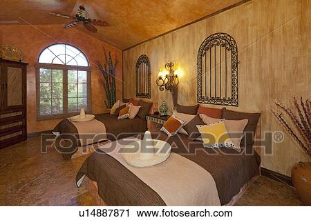 Stock Image - Modern bedroom interior with straw hats on twin beds in mansion. Fotosearch