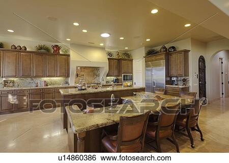 Stock Photograph - Modern counter with chairs in kitchen of luxury mansion. Fotosearch