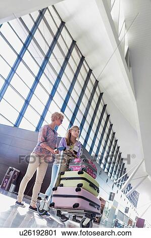 Mother and daughter pushing cart with their luggage for check in at airport View Large Photo Image Stock Image - Mother and daughter pushing cart with their luggage for check in at airport. Fotosearch
