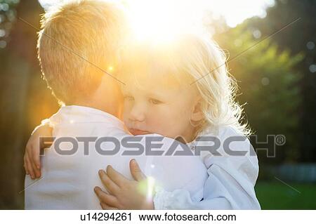 Stock Image - Mother hugging child in summer scene. Fotosearch