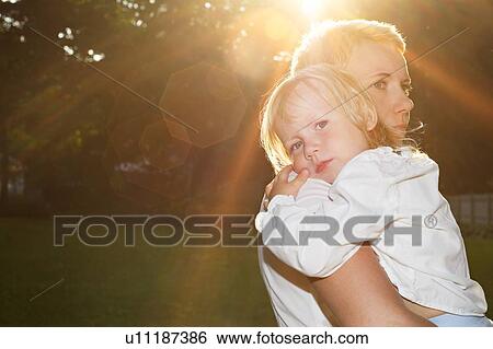 Stock Photograph - Mother hugging child in summer scene. Fotosearch
