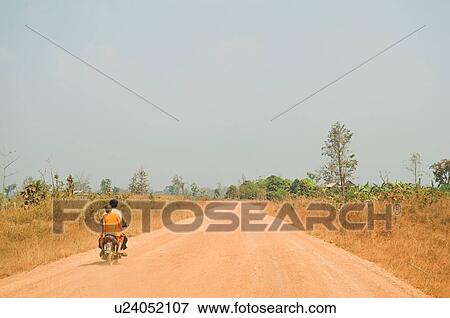 Stock Photo - Motorcyclist Giving Ride to Young Monk on Rural Road. Fotosearch